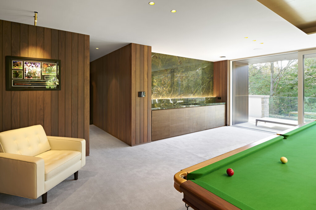 A corner of the snooker table in the foreground with the lit marble bar behind