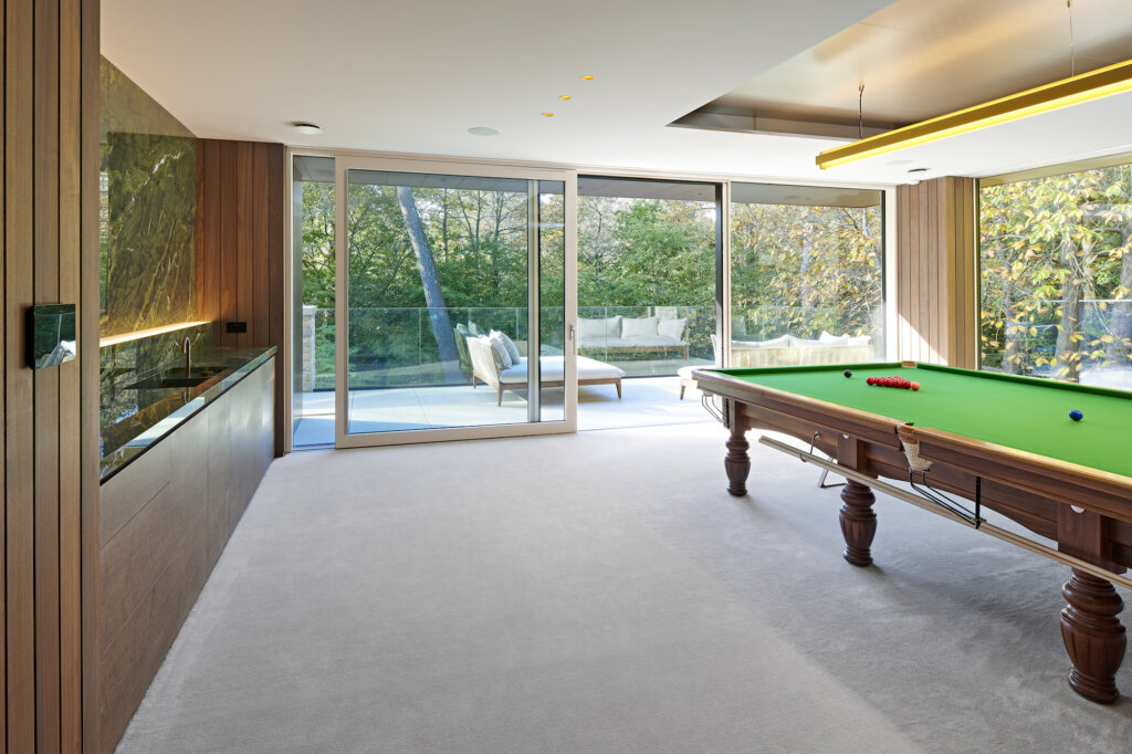 A view between the bar and snooker table through the open sliding glass doors to the balcony and the treetops