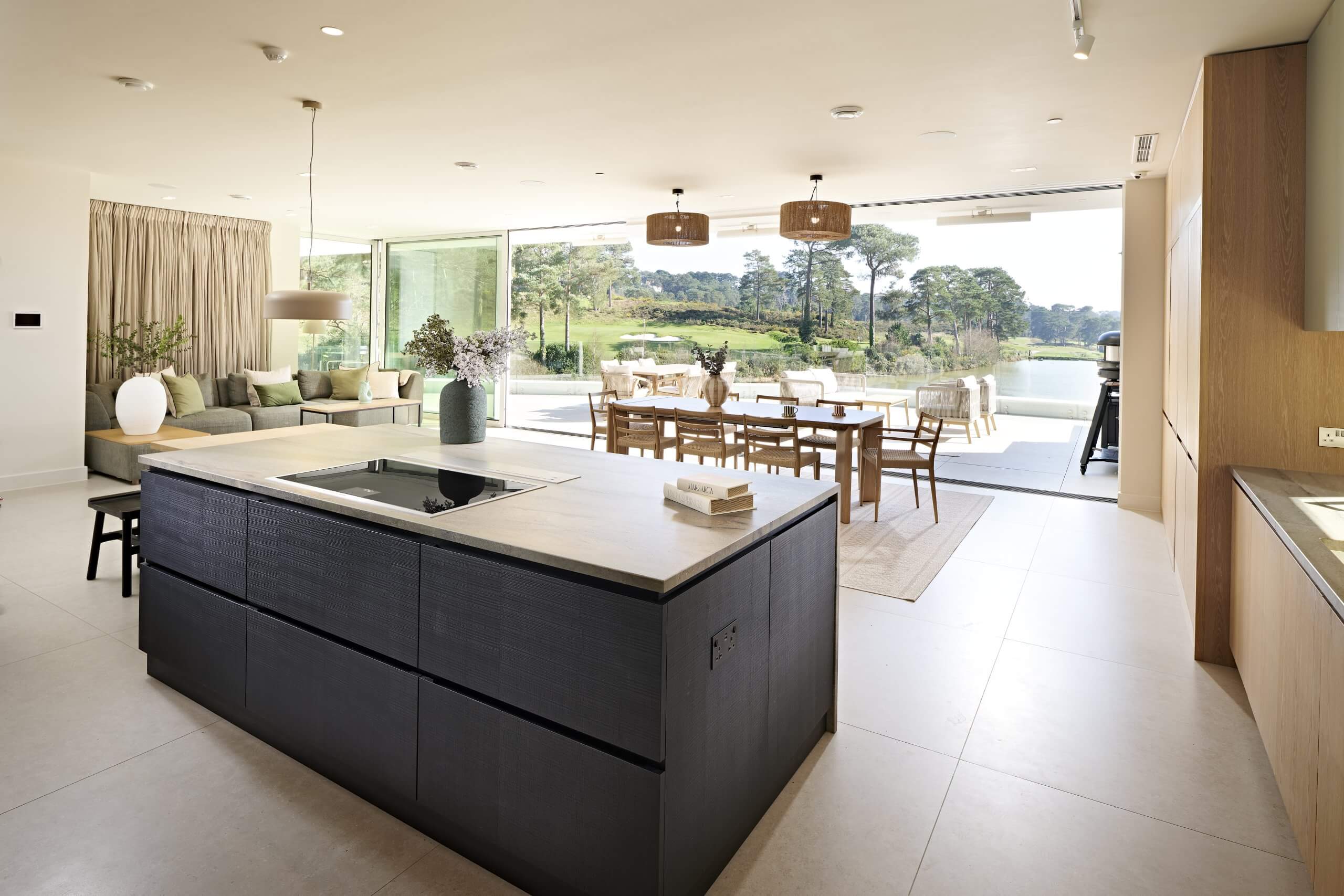 View of the Hidden Lake kitchen from the Utility room showing the island and the view across the lake to the golf course with the sliding glass wall open